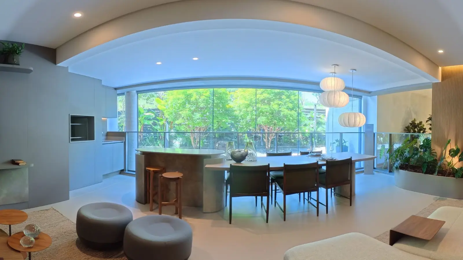 Living integrado com mesa de jantar e parede de vidro para a área verde, em foto 360º