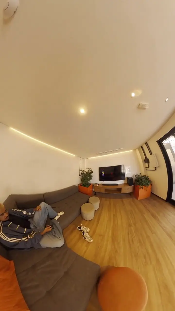 Lounge com sofás baixos, pufes e janelas amplas, em vídeo 360º reenquadrado